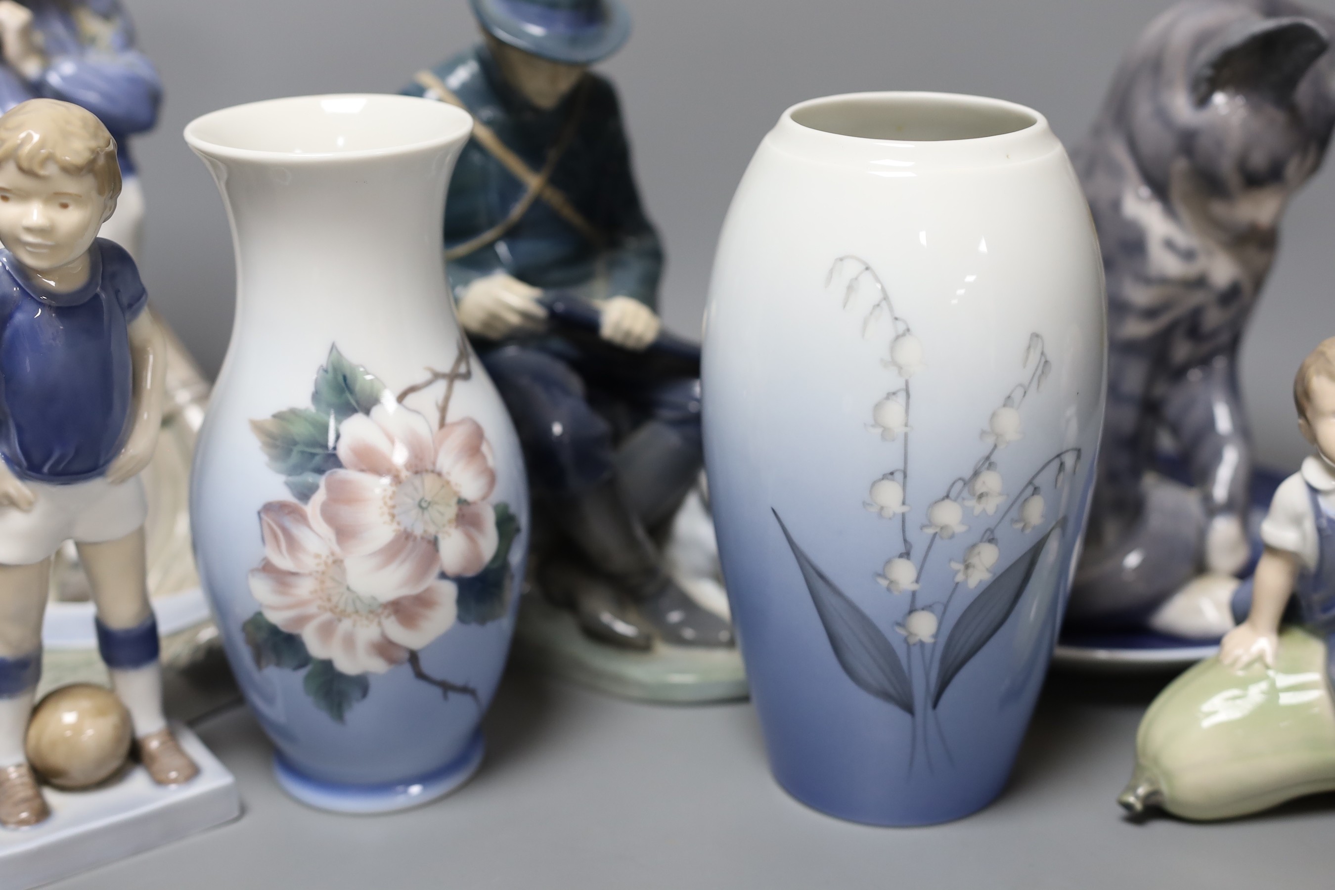 Eight pieces of Royal Copenhagen, to include a seated cat 340, Christmas Rose and Cat plate, a seated farm boy 4539, a young footballer 5657, two floral vases 2630 2289 and 57/251 K.P, a seated huntsman with dog 1087, an